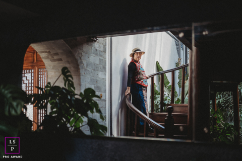 Framed through the dark interior in Yunnan, this quiet figure pauses on the staircase with calm confidence and mystery. The layered composition, soft window light, and surrounding shadows give the photograph depth, elegance, and cinematic restraint.