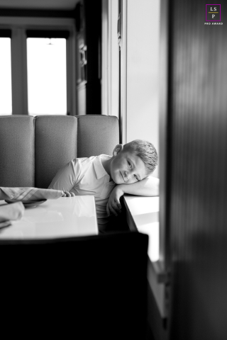 In Charleston, South Carolina, the young boy rests quietly against the restaurant windowsill, lost in a sleepy moment of stillness. The black and white tones and narrow framing give the portrait softness, calm, and a beautifully reflective mood.