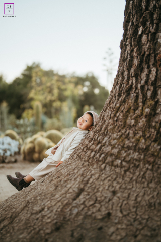 At Stanford, the little boy leans happily against the massive tree trunk as though the tree itself were part playground, part hiding place. The oversized scale and soft natural tones give the portrait charm, curiosity, and childhood wonder.