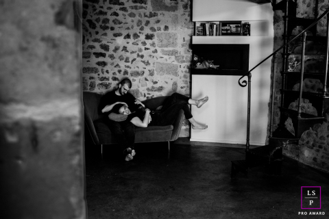 In Montpellier, France, the couple relaxes together on a small sofa tucked inside their stone apartment. The black and white tones and wide negative space give the portrait intimacy, stillness, and a beautifully lived-in feeling.