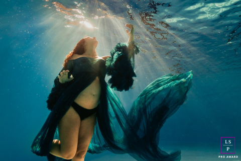 In Châteauroux, France, the expectant mother floats beneath the water as light pours down around her flowing dress. The underwater movement and soft rays create a maternity portrait that feels peaceful, weightless, and beautifully ethereal.