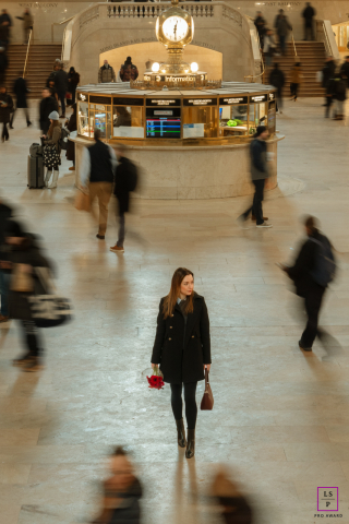 Inside Grand Central Terminal in NYC, the woman moves calmly through the blur of rushing commuters, holding bright red flowers like a small act of defiance against the city’s relentless pace. The motion and symmetry give the portrait cinematic energy.