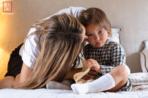 Mother Cuddles Young Daughter During Quiet Time Together In Indre France A mother gently cuddles her young daughter as they share a quiet time together on a bed in Indre, France.
