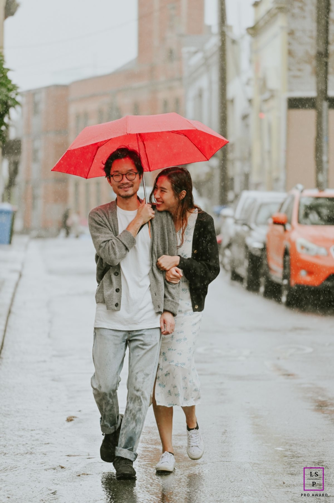 Utrecht couple portrait session for a Netherlands lifestyle image created during Sudden heavy rain with their umbrellas covering the couple walking in the rain and being romantic