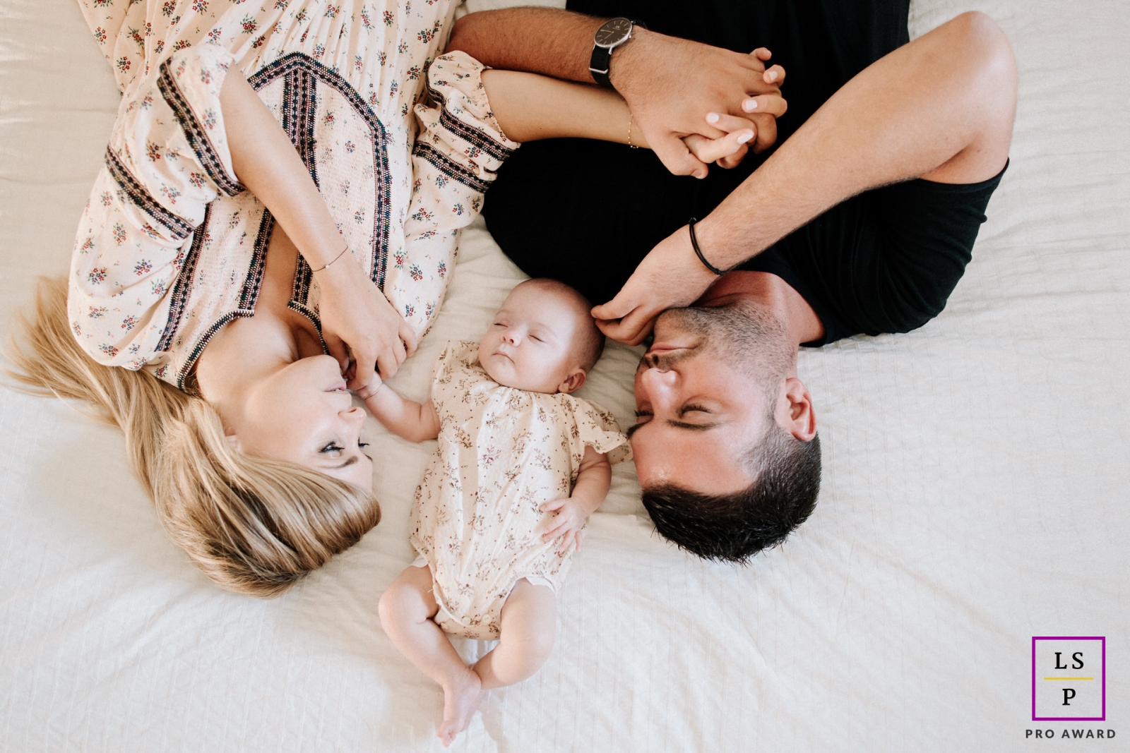 Auvergne-Rhone-Alpes new parents lying down with baby on the bed for an overhead portrait in bed