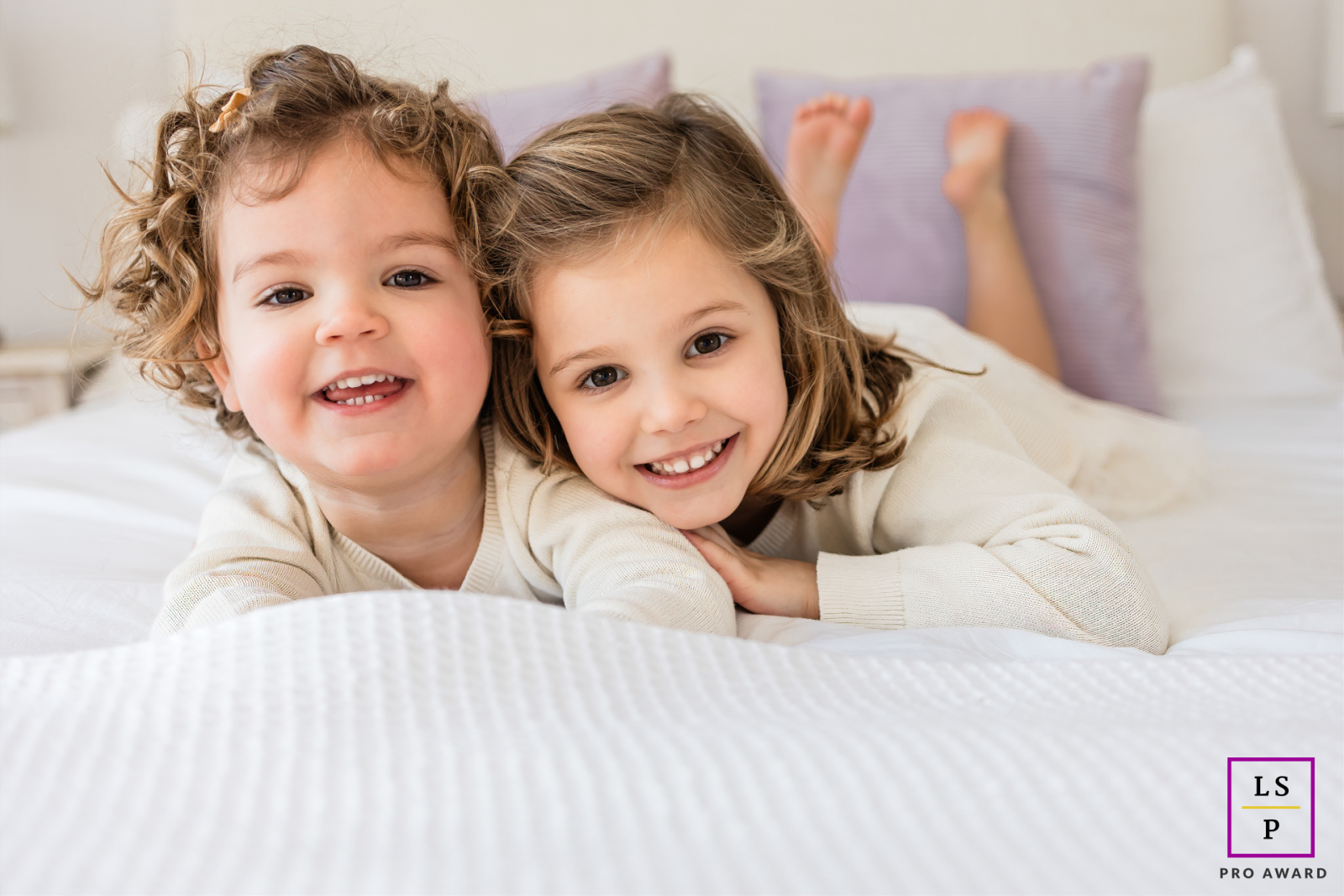 On the East Coast, New Jersey, little girls lie close together on a bed, sharing sweet and tender smiles.
