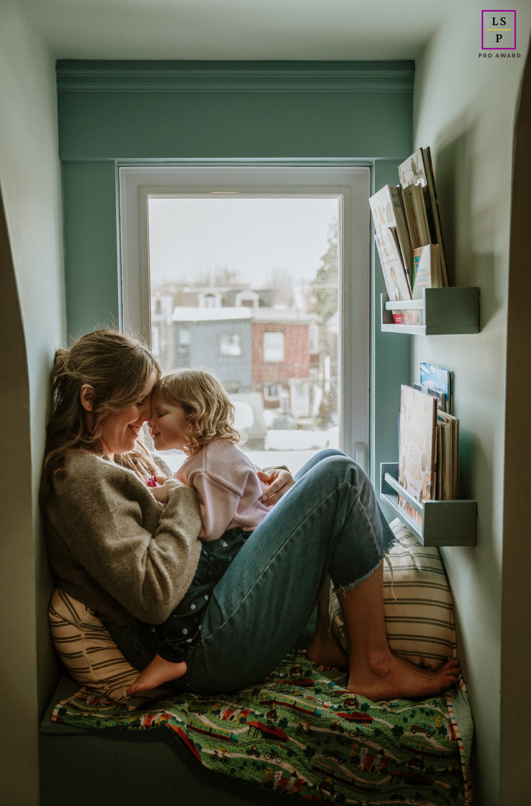 Curled together in a narrow Toronto window nook, this mother and daughter share the kind of closeness that silences the outside world. The soft natural light and intimate framing give the photograph warmth, tenderness, and quiet emotional depth.