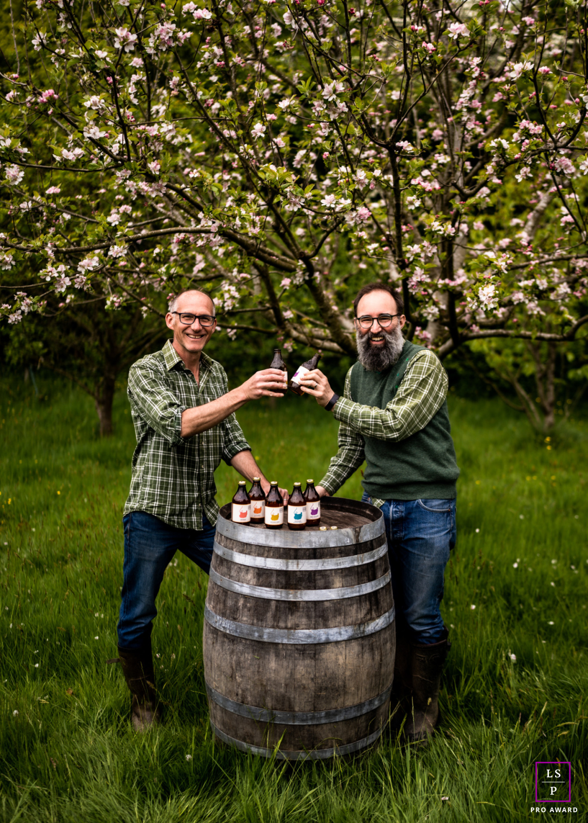 Portrait professionnel de Bignose & Beardy (également connus sous le nom de Phil & Steve) dans leur siège social pittoresque situé dans un verger à Framfield, dans l'East Sussex, au Royaume-Uni. Les deux hommes brandissent fièrement une bouteille de leur cidre fraîchement brassé.