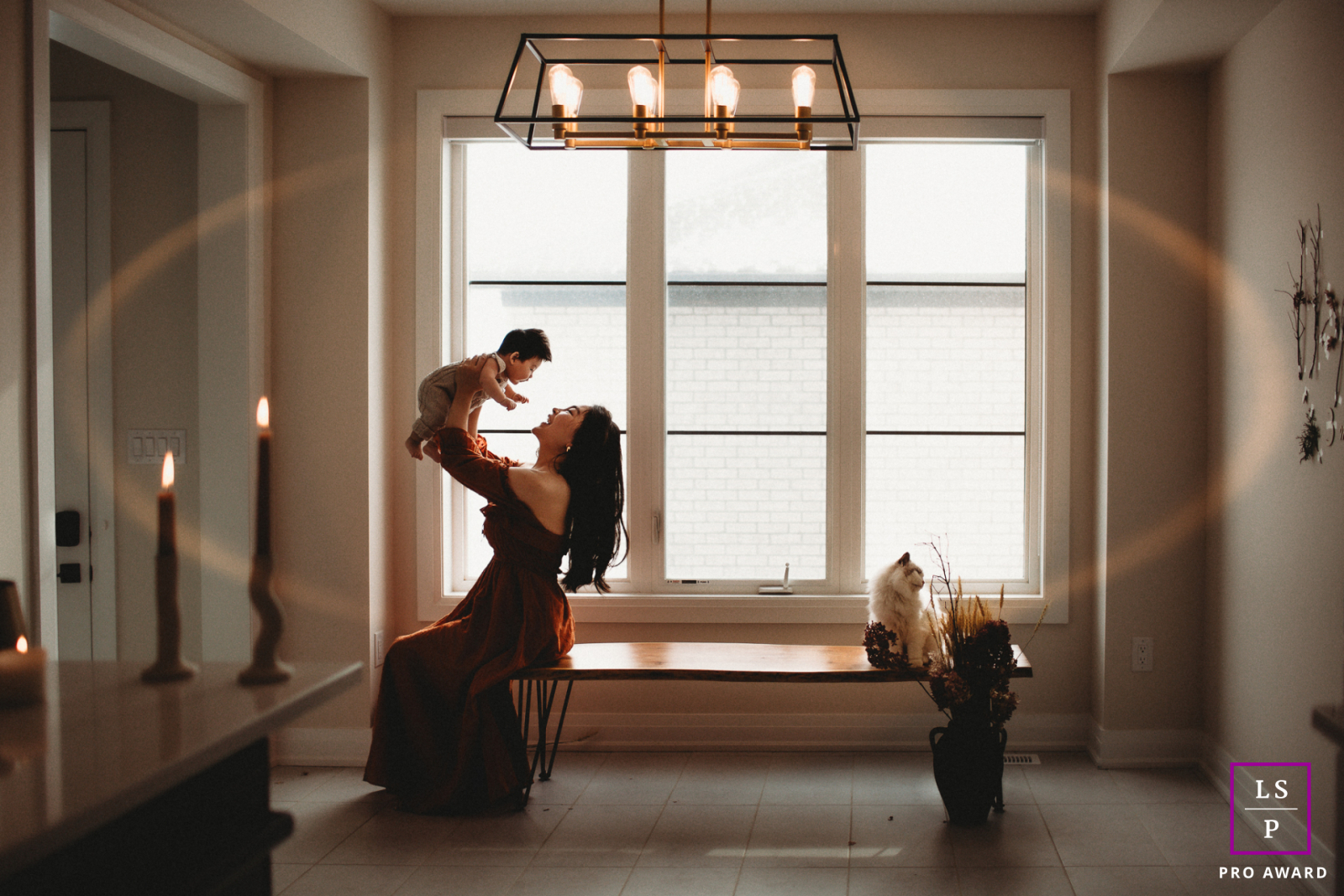 In Markham, Ontario, under the gentle glow of candlelight, a mother's love silently shines. Despite her weariness, she lifts her baby with unwavering strength, a promise to support them through life's journey. Her love, like the flickering flame, remains 