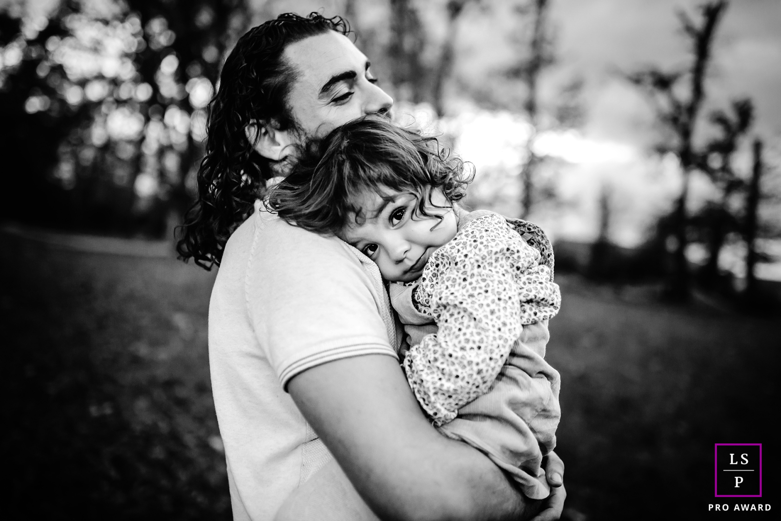 In Isère, France, a black and white photo captures a heartwarming scene of a child finding comfort in their father's embrace.