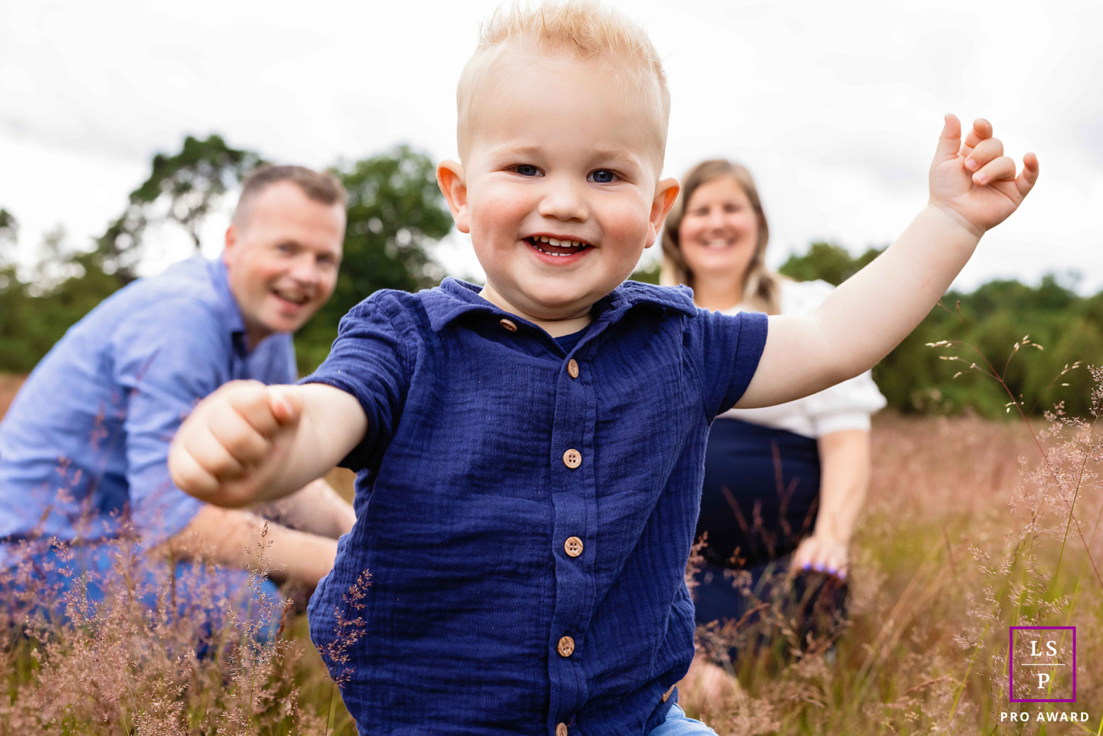A happy child runs toward the photographer in Overijssel, Netherlands. Their arms are outstretched, and they have a wide smile, filled with joy and excitement.