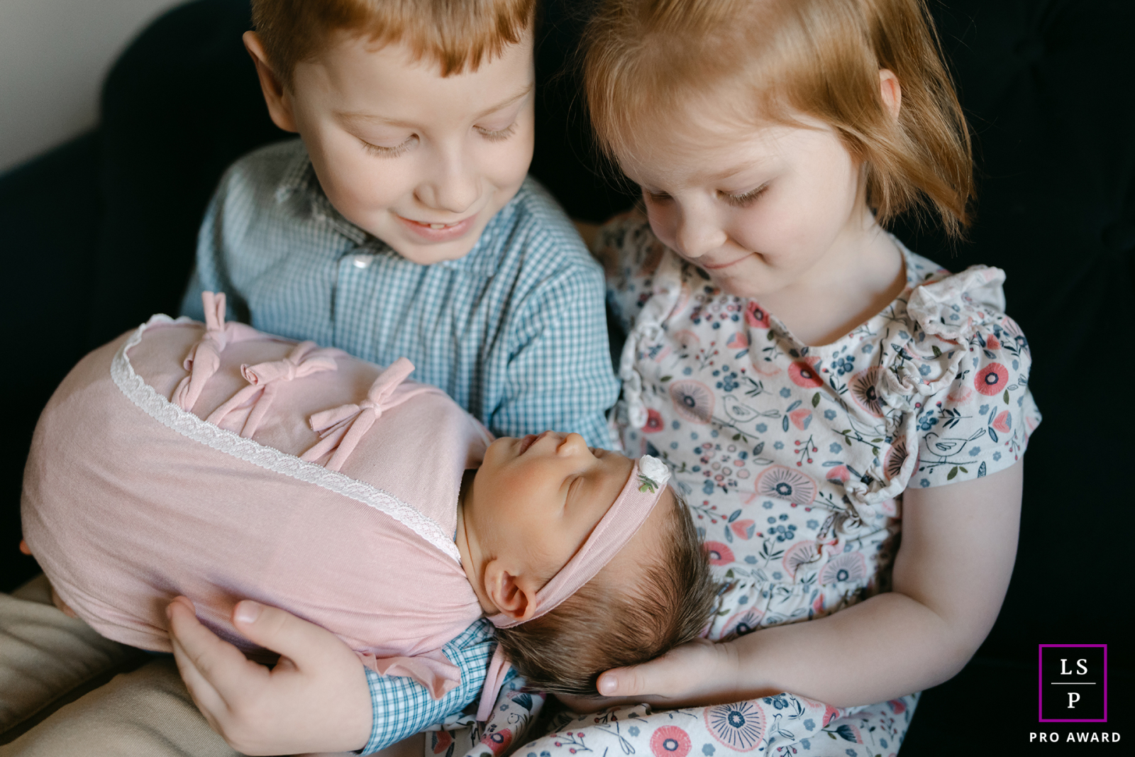 In West Bend, these young siblings cradle their newborn sister with complete attention and quiet pride. The soft light and close framing highlight their gentle expressions, turning the photograph into a tender study of early sibling love.
