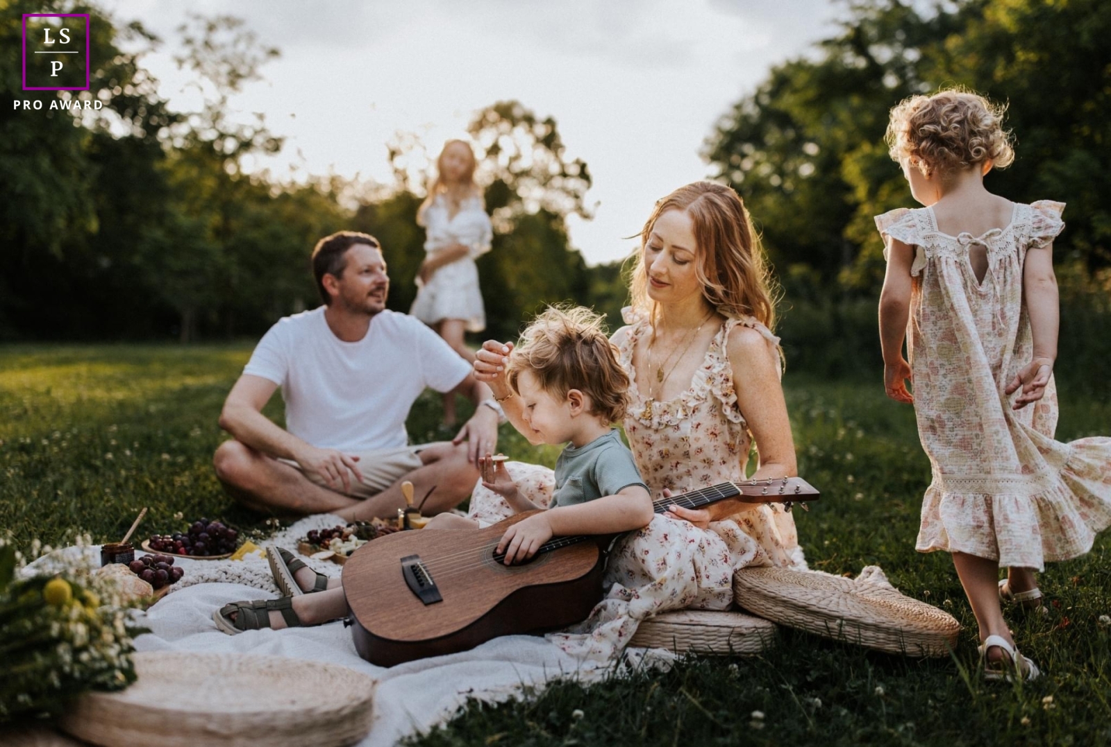 Lifestyle photography from Portland to show the lives of these parents and three children having a Picnic on a blanket in an open field