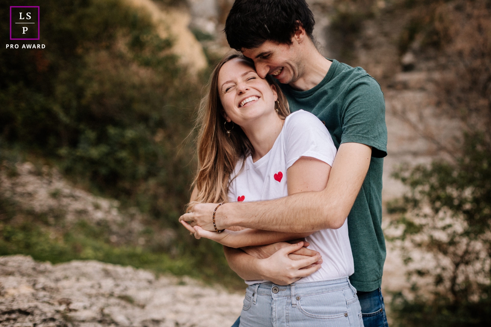 In Ardeche, France, two lovers find joy in each other's company, captured in a lifestyle portrait where laughter intermingles with cuddles