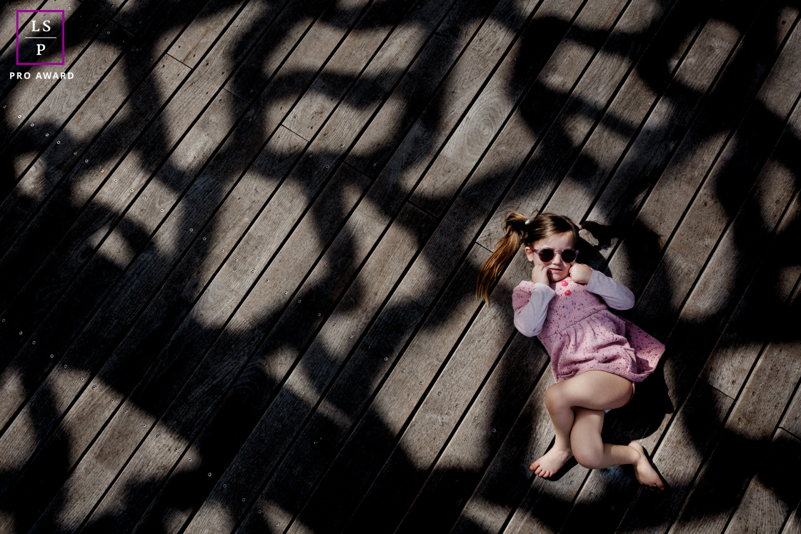 Portrait of a cheeky little girl in Paris, basking in the sun as the shadows add a graphic touch to the lifestyle scene.