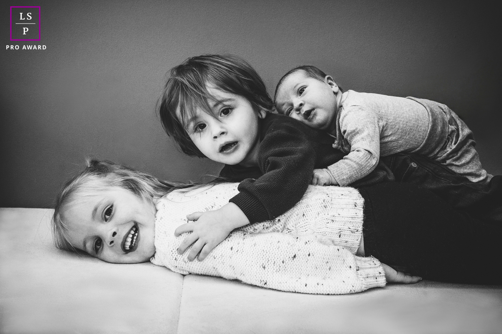 In Arnprior, three siblings pile together with the kind of playful chaos only children can create naturally. The black and white tones simplify the scene beautifully, allowing the expressions, tiny gestures, and layered affection to carry the photo.