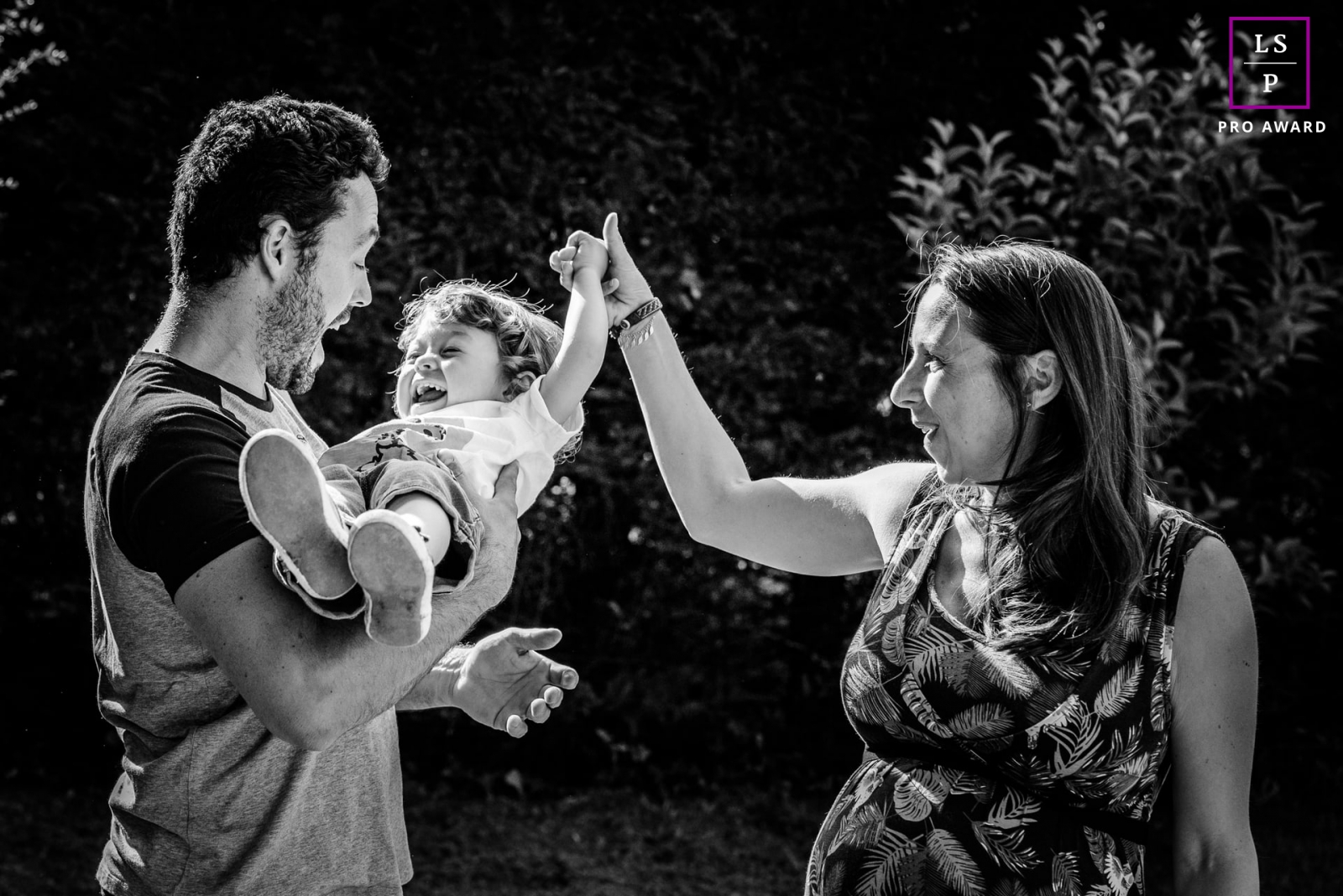 Occitanie Lifestyle Family Portraits in Haute-Garonne | Image contains: mom, dad, toddler, child, park, trees, sun, black and white