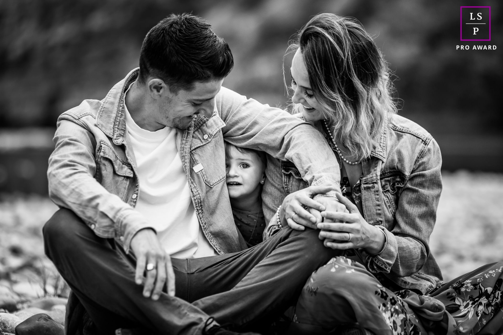 A modern Ardeche lifestyle photography session that shows a young girl playing hide and seek behind seated parents