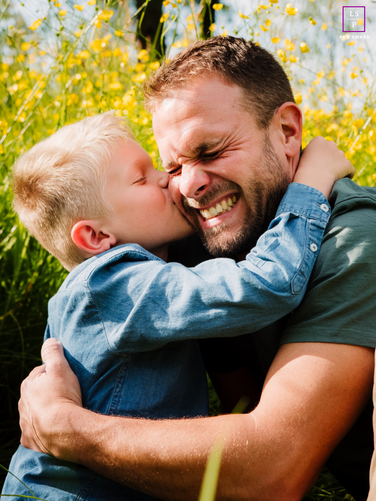 The father’s squinting grimace of pure delight is the first layer, followed by that tight, denim-clad embrace. This masterfully captured moment radiates a raw, joyous connection amidst the buttery floral backdrop.