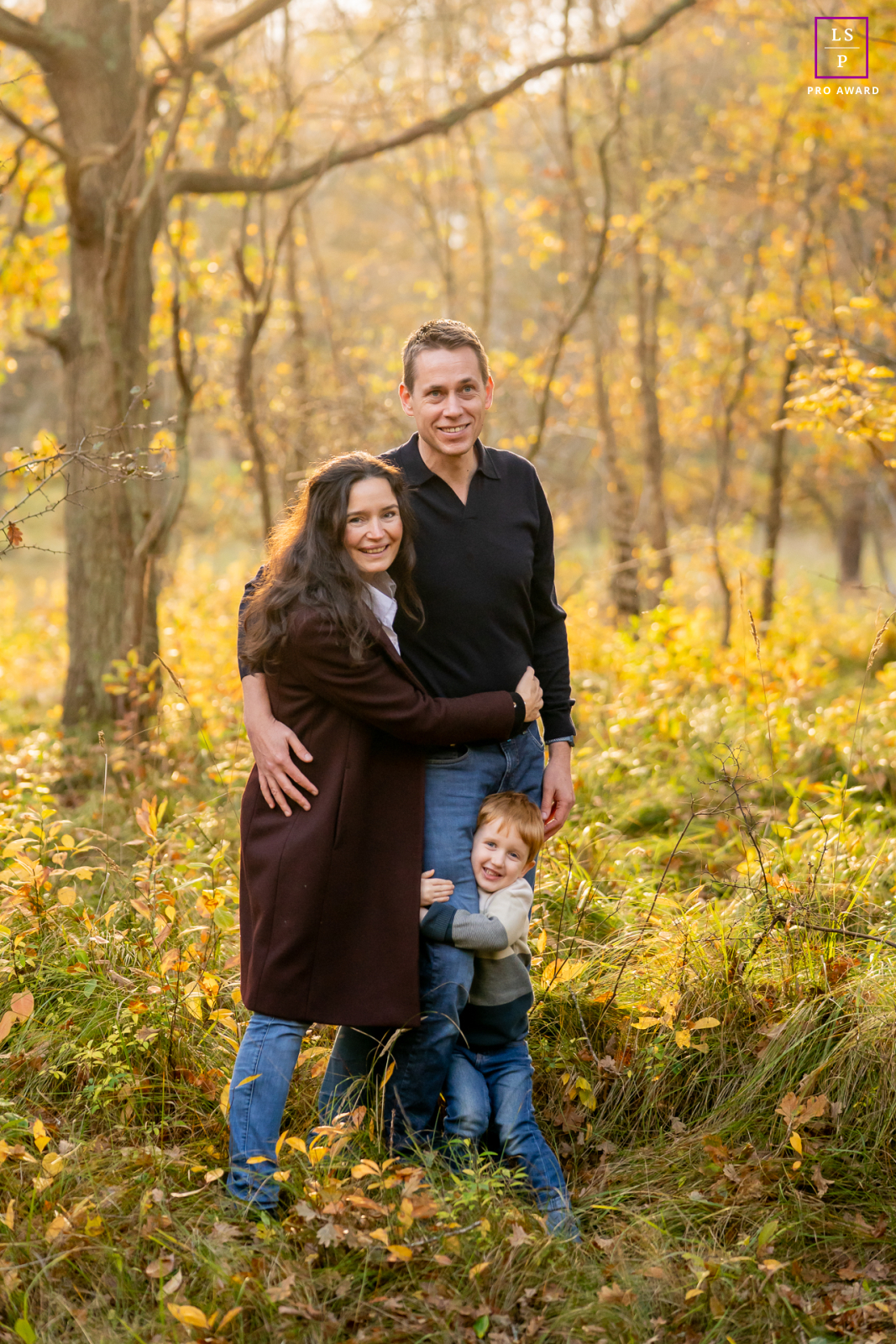 Surrounded by autumn brush in Meijendel, this family folds into one another with the easy closeness that cannot be rehearsed. The child’s playful grip adds charm, while the warm woodland light wraps the photograph in comfort and quiet connection.