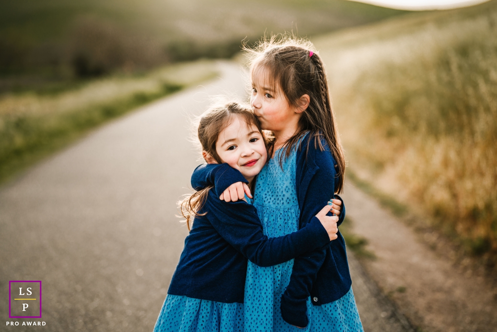 A modern image from San Jose to help define lifestyle photography by showing two sisters hugging and kissing on a rural road