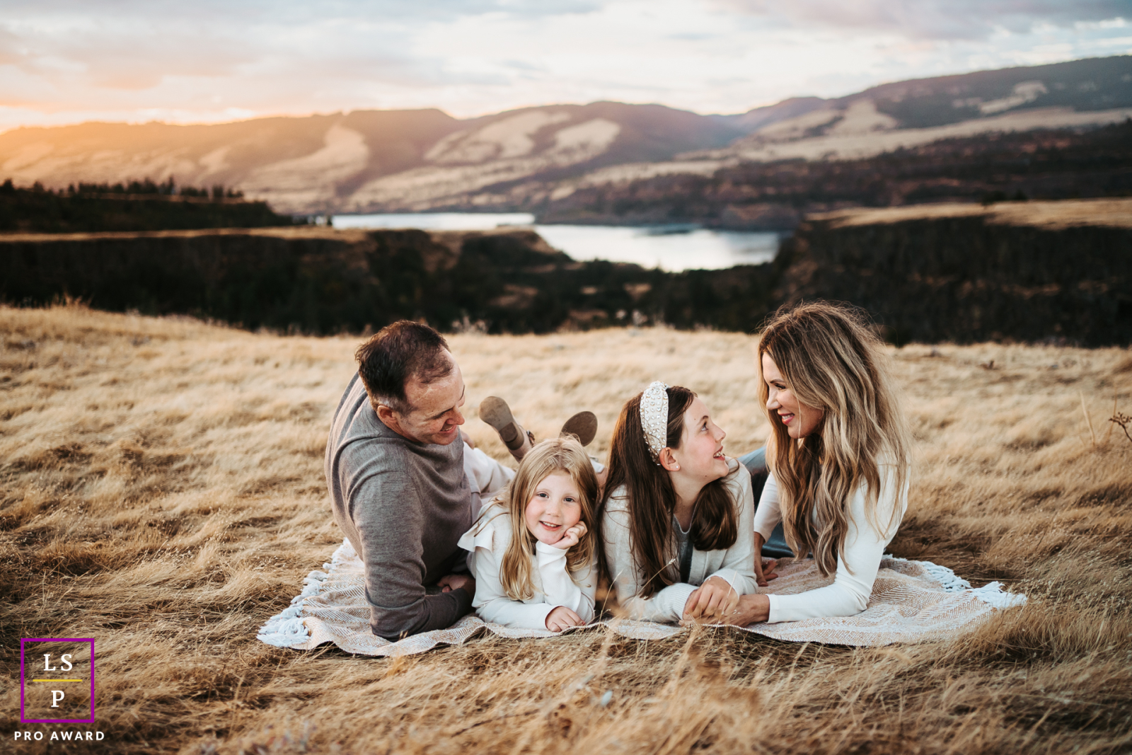 In Washington, USA, a beautiful family relaxes on a blanket in a dry grass field at the gorge, enjoying their time together.