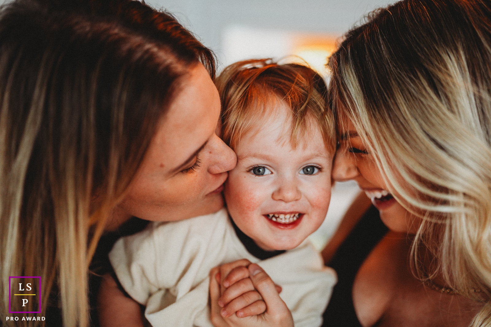 In this Boston home, a child beams between two loving embraces, completely aware of being the center of attention. The tight framing and warm tones pull every ounce of joy and connection directly toward the viewer.