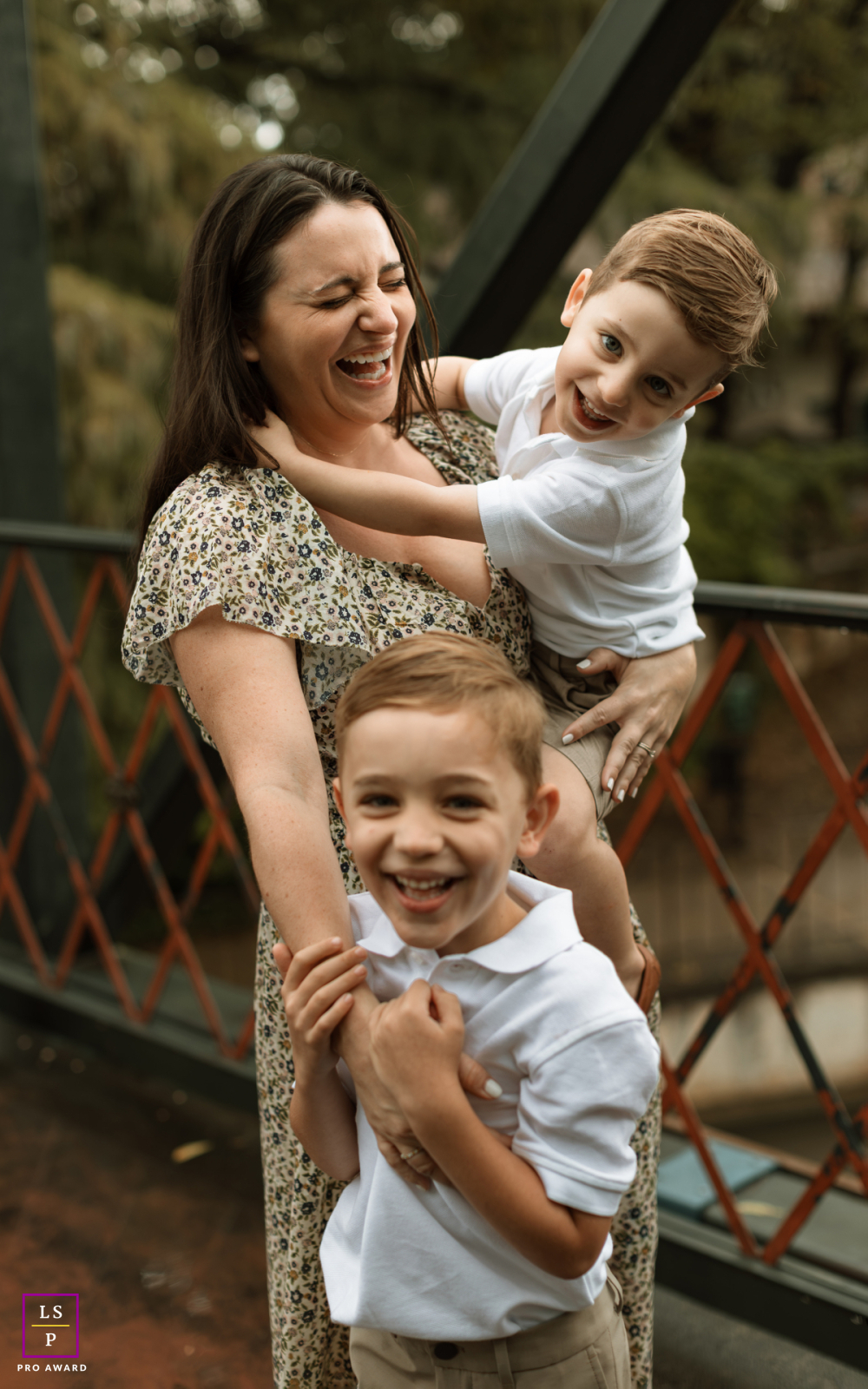 In San Antonio, Texas, the mother bursts into laughter as her two boys cling to her with playful energy. The close framing and natural expressions fill the portrait with warmth, movement, and joyful family connection.