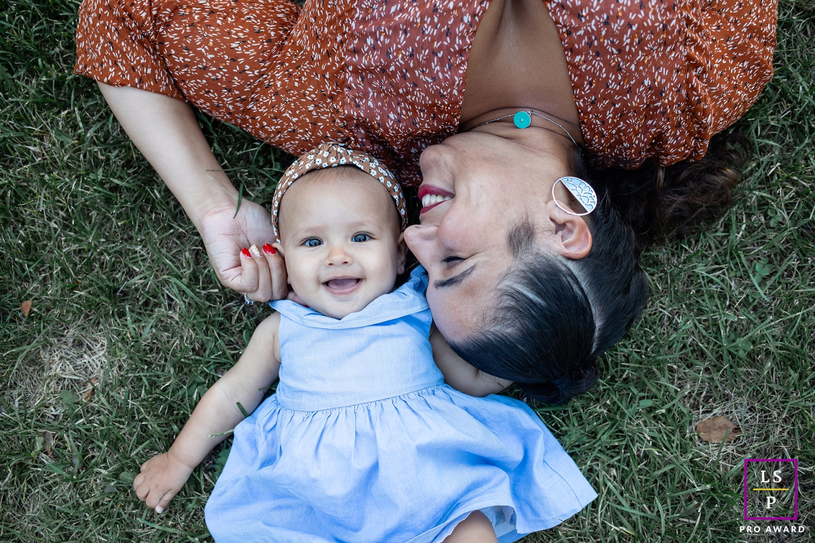 This charming lifestyle portrait captures a mother and daughter, as they lie on their backs in the grass in Dijon, France