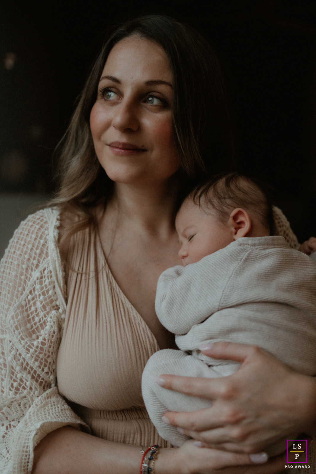 In the South-West of France, a young mother cradles her sleeping newborn in soft window light with quiet tenderness. The muted tones and gentle shadows give the photograph warmth, intimacy, and the peaceful stillness of early motherhood.