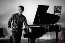 A Lifestyle Portrait at GK Piano in San Jose, California A lifestyle photographer took a black and white picture of a man standing next to a grand piano at GK Piano in San Jose, CA.