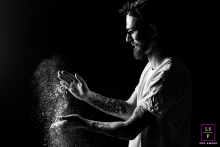 In Cauneille, the baker tosses flour into the air like a stage magician revealing his craft. The black background and dramatic side light transform drifting particles into something almost celestial, while the tattoos and profile add modern grit.