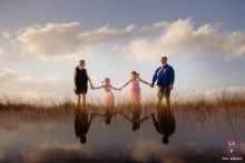 Family reflections during Lifestyle portraits in grass with clouds overhead Key West Florida Family reflections - Lifestyle portraits in grass with clouds overhead.