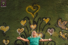 lifestyle image from urban wall art of a woman standing before a heart and butterfly flower mural and emanates love This is a lifestyle image from Campo Grande of a woman standing before a heart and butterfly flower mural and emanates love