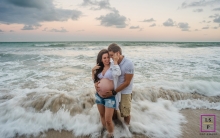 This is a lifestyle image from Maceio as the couple are embraced in the sea water and The man embraces his pregnant wife and her belly