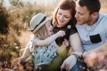 A professional lifestyle family photo from Ain showing a little girl gives a gift to these parents