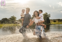 A Campo Grande candid image from Mato Grosso do Sul that is defining what a lifestyle portrait is by showing a young happy family running on the lake A Campo Grande candid image from Mato Grosso do Sul that is defining what a lifestyle portrait is by showing a young happy family running on the lake