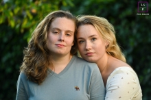 Two sisters from Utrecht, Netherlands pose together with faces close under trees