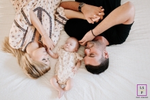 Auvergne-Rhone-Alpes new parents lying down with baby on the bed for an overhead portrait in bed