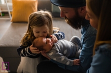 From Provence, a loving family was captured in a lifestyle photography session as the little girl kissed her baby brother on the forehead while her father held him In France, Provence, a little girl kissed her little brother on the forehead while her parents watched. The father was holding the baby.
