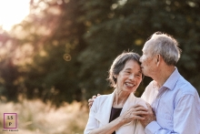At sunset in Sammamish, Washington, this elderly couple is taking their first family lifestyle photo after the husband's three heart surgeries, sealing it with a loving kiss