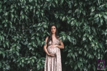 A woman peacefully stands among a backdrop of vibrant green leaves in this stunning maternity portrait in Maceio