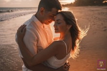 A couple embraces each other as they stand on the sandy beach during a beautiful sunset in Maceio