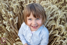 A child stands in a sunlit field of golden grain in Dijon, beaming with a big smile, as an overhead shot captures their joyous lifestyle portrait