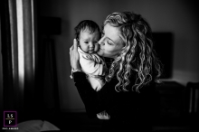 Capturing love in Provence, France: A tender embrace illuminated by ethereal window light In the warm embrace in Provence, France, a tender moment unfolds as a glowing mother presses a gentle kiss upon her baby's cheek, enveloped by the delicate touch of ethereal window light
