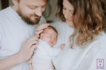 Elegant Family Portrait: Parents and Baby in White Attire in Hauts-de-France A family portrait in Hauts de France, featuring parents and their baby, all dressed in white attire.