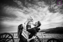 A Joyful Family Countryside Portrait in Hérault's Beauty In Hérault, a joyful family photograph captures parents lifting their baby high into the air, their faces filled with joy and laughter, set against a backdrop of beautiful natural scenery.