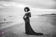 Seaside Serenity: A Glowing Expectancy in Hérault In Hérault, a maternity photograph captures a glowing expectant mother standing on the beach, wearing a beautiful maternity dress that flows gently in the seaside breeze, with the waves softly lapping at the shoreline behind