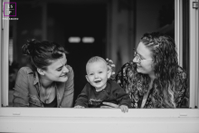 Deux femmes de la Loire jouent amoureusement avec un enfant entre elles, tandis qu'elles regardent par la fenêtre.