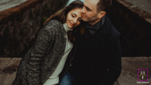 In Lucca, Toscana, Italia, a tender portrait captures a couple by the water. She leans into him, reflecting their deep connection and affection amidst the picturesque surroundings.